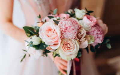 Brides wedding bouquet with peonies, freesia and other flowers in women's hands. Light and lilac spring color. Morning in room